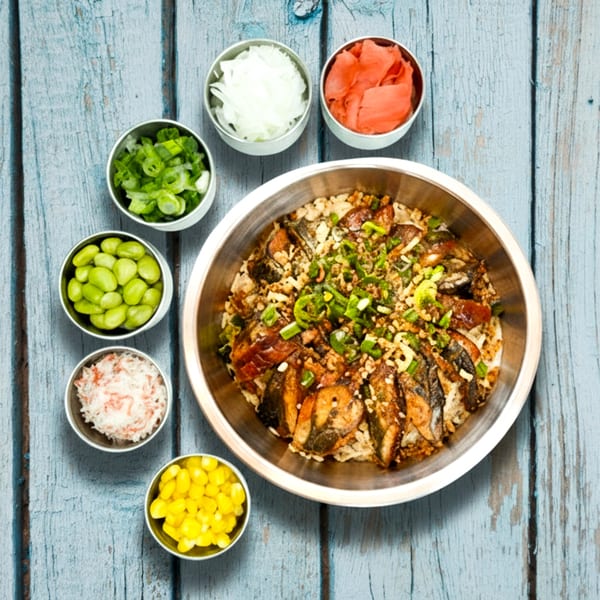 Sunfish Poke Bar's poke bowl with fish, rice, and various toppings on a blue wooden table.