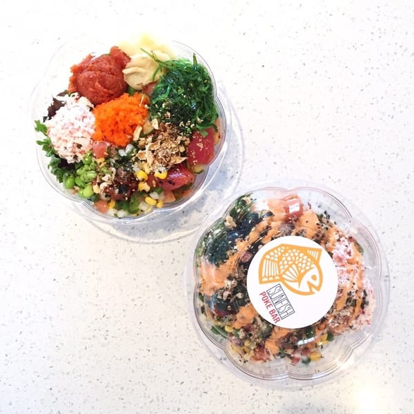 Two colorful Sunfish Poke Bar bowls, one open and one closed with a logo sticker, on a white counter.